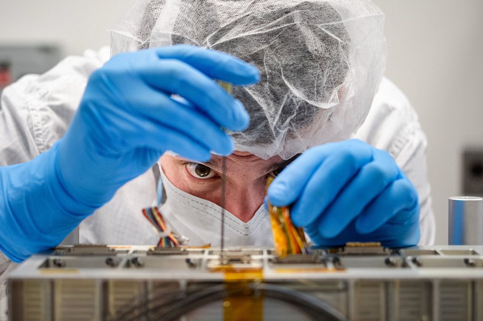 A technician installs a connector on LISA's laser optical module at NASA's Goddard Space Flight Center